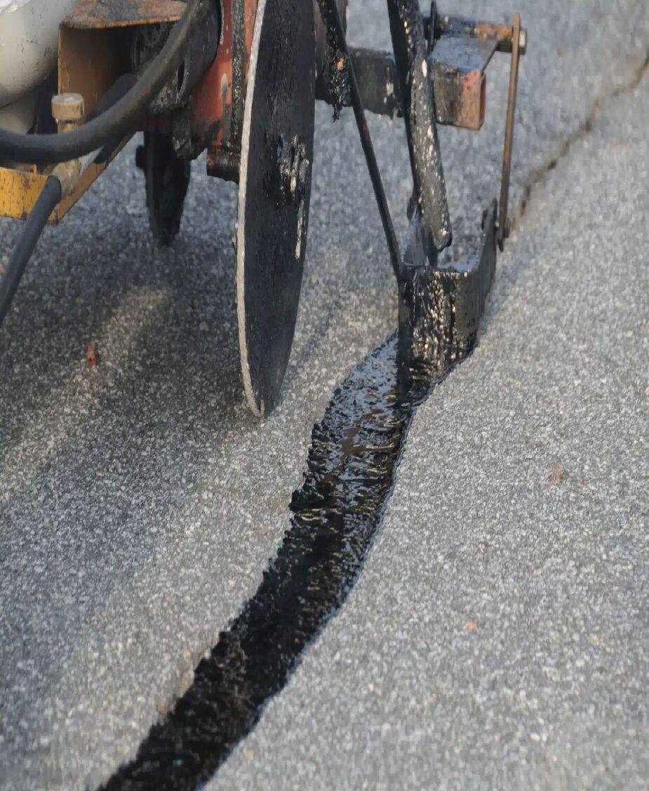 Hot rubberized crackfill applied to asphalt driveway cracks