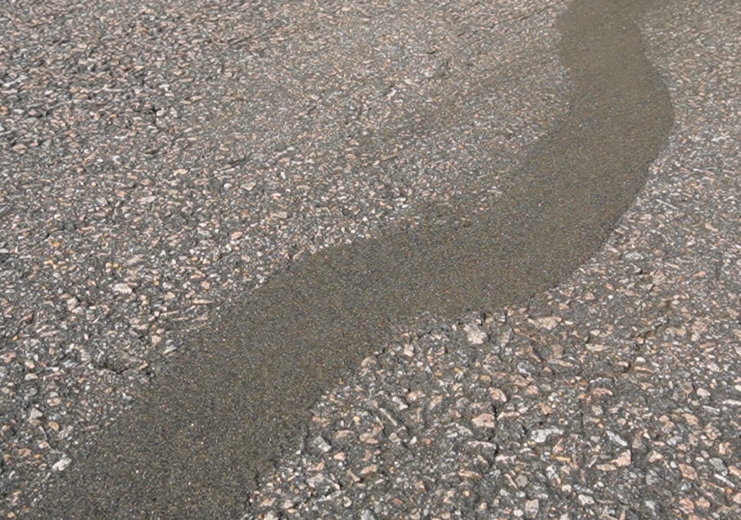 Sanded hot rubber crackfill strips on residential driveway