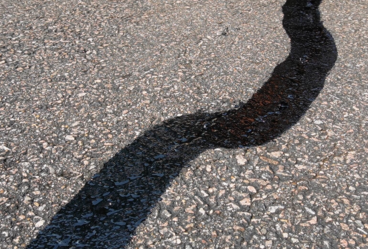 Hot rubberized crackfill applied at 350 degrees to asphalt cracks